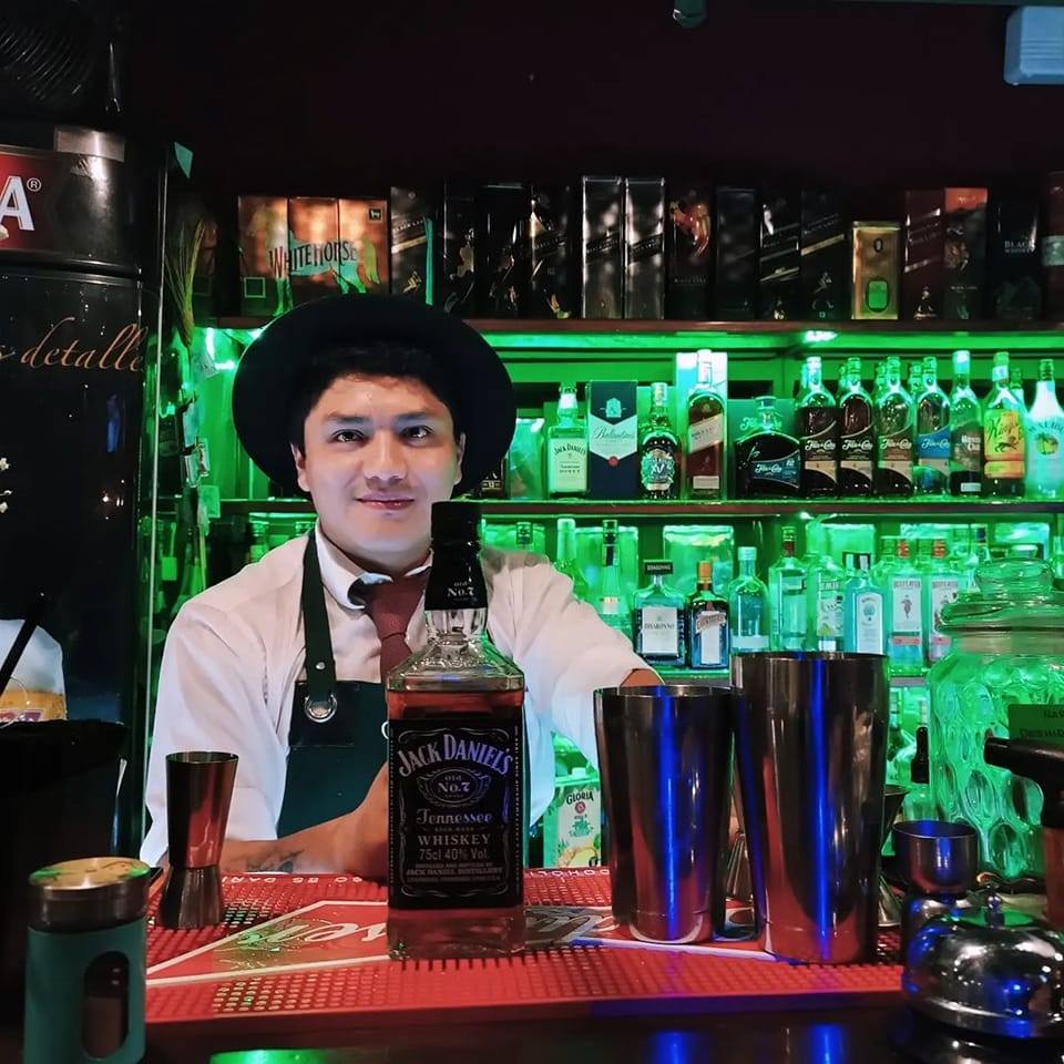 Alejandro Pinzón preparando cócteles, sonriendo y sirviendo bebidas artesanales